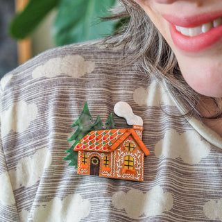 Model wearing the Erstwilder Brooch The Sweetest Cabin from the Merry Menagerie Collection — a festive gingerbread house brooch with candy roof, pine trees, and hand-painted detailing, available at Pink Poppies Living Creatively Stanthorpe.